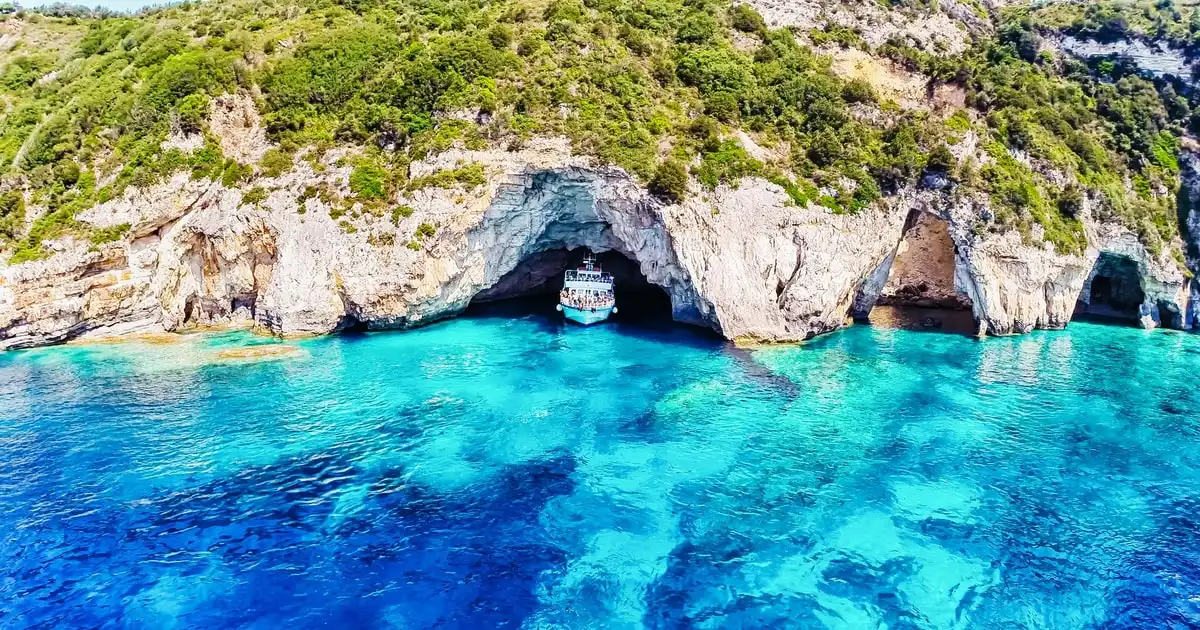 Large cruise boat off the white cliffs of Paxos on a full-day Corfu boat tour to the Paxos blue caves