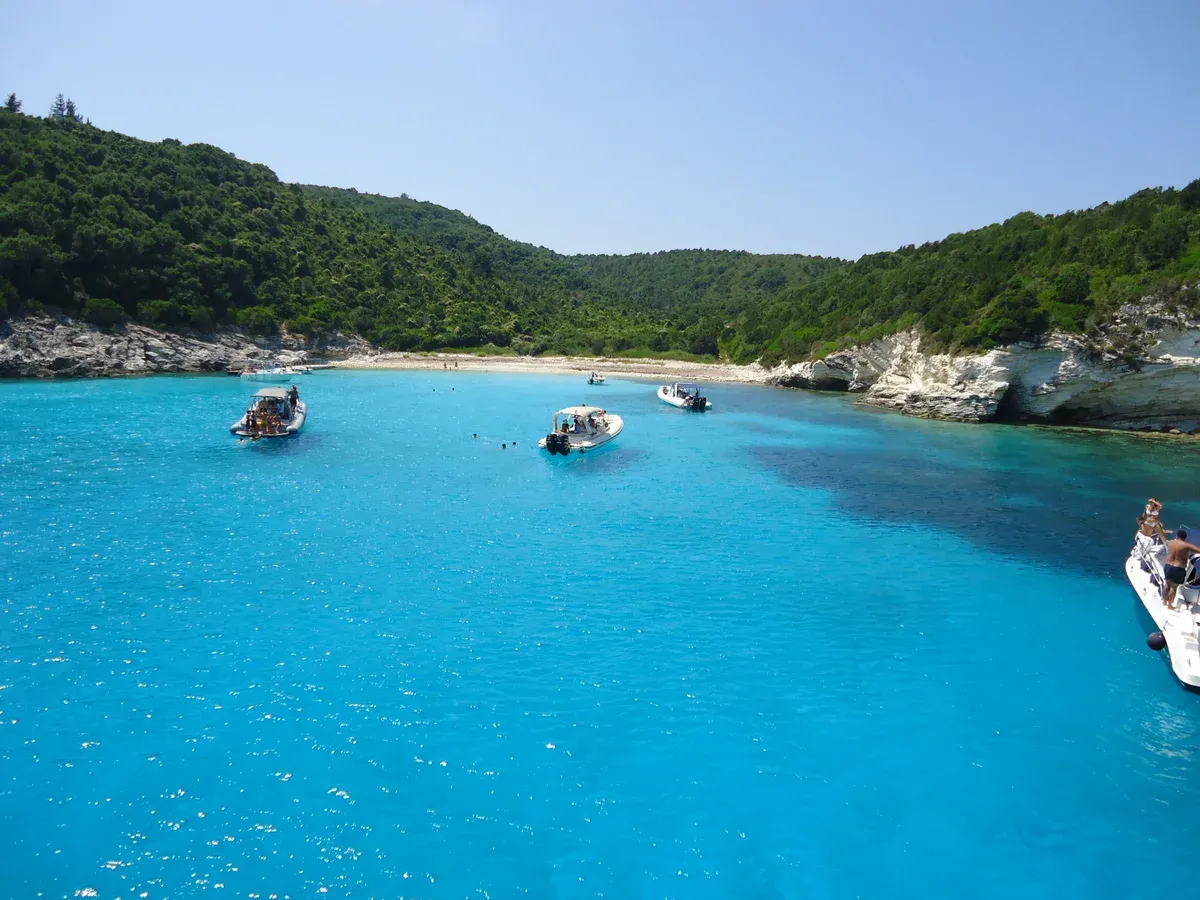 Boats anchored in turquoise water off Voutoumi beach on Antipaxos during a Corfu boat tour